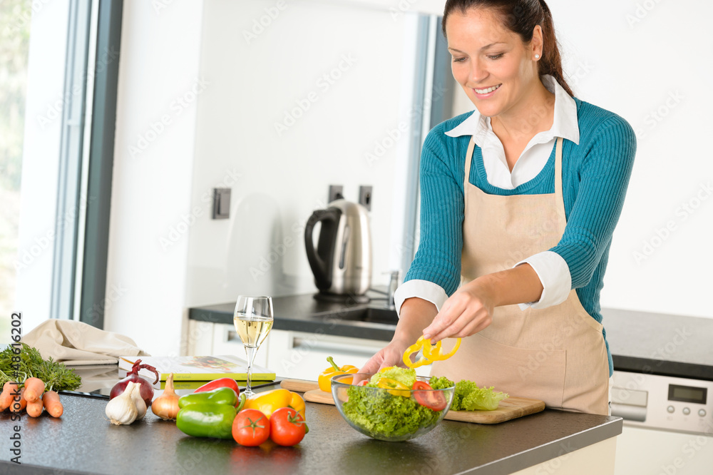 Happy woman making salad kitchen vegetables cooking