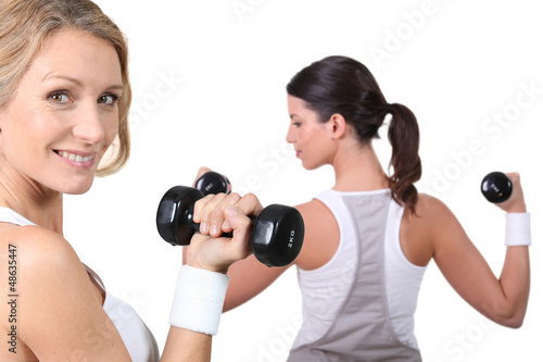 Two women lifting weights together