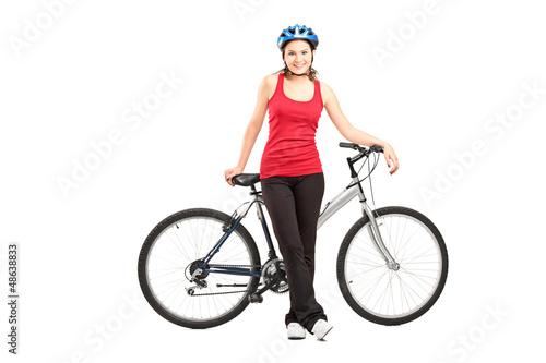Female biker with helmet posing next to a mountain bike
