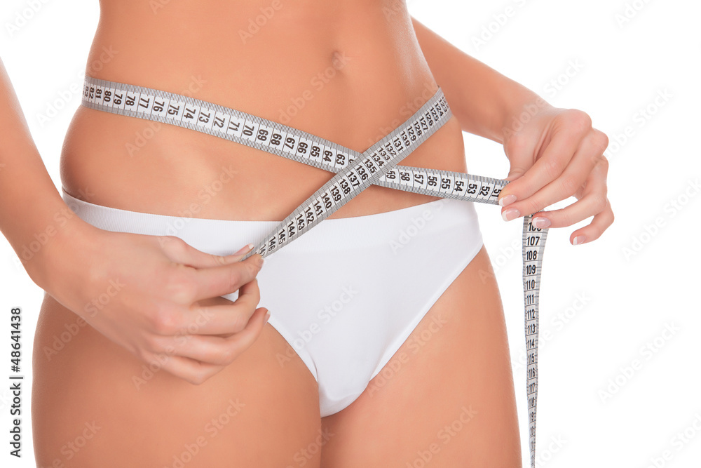 fit young woman measuring her waistline, white background