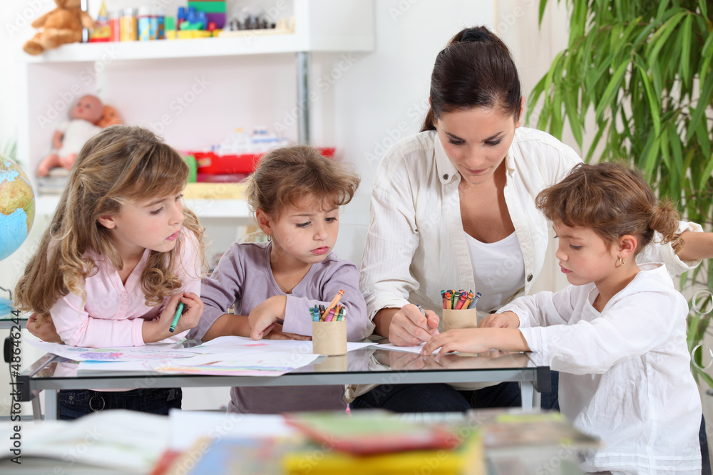 Fototapeta premium Woman helping a group of girls with their homework
