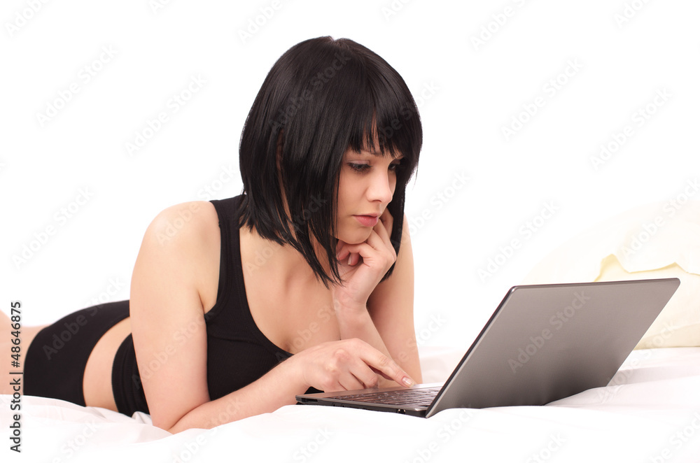 Cute young female lying with laptop in the bed Cute young female lying with laptop in the bed