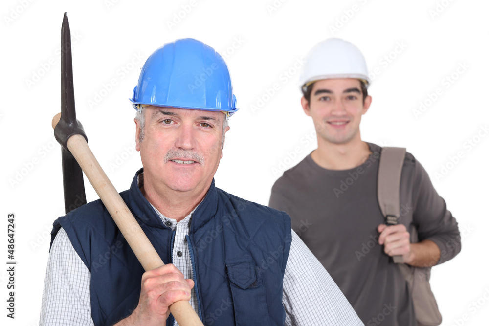 mature manual worker and young apprentice in background mature manual worker and young apprentice in background