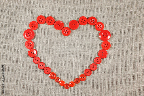 Heart in shape of red buttons on fabric