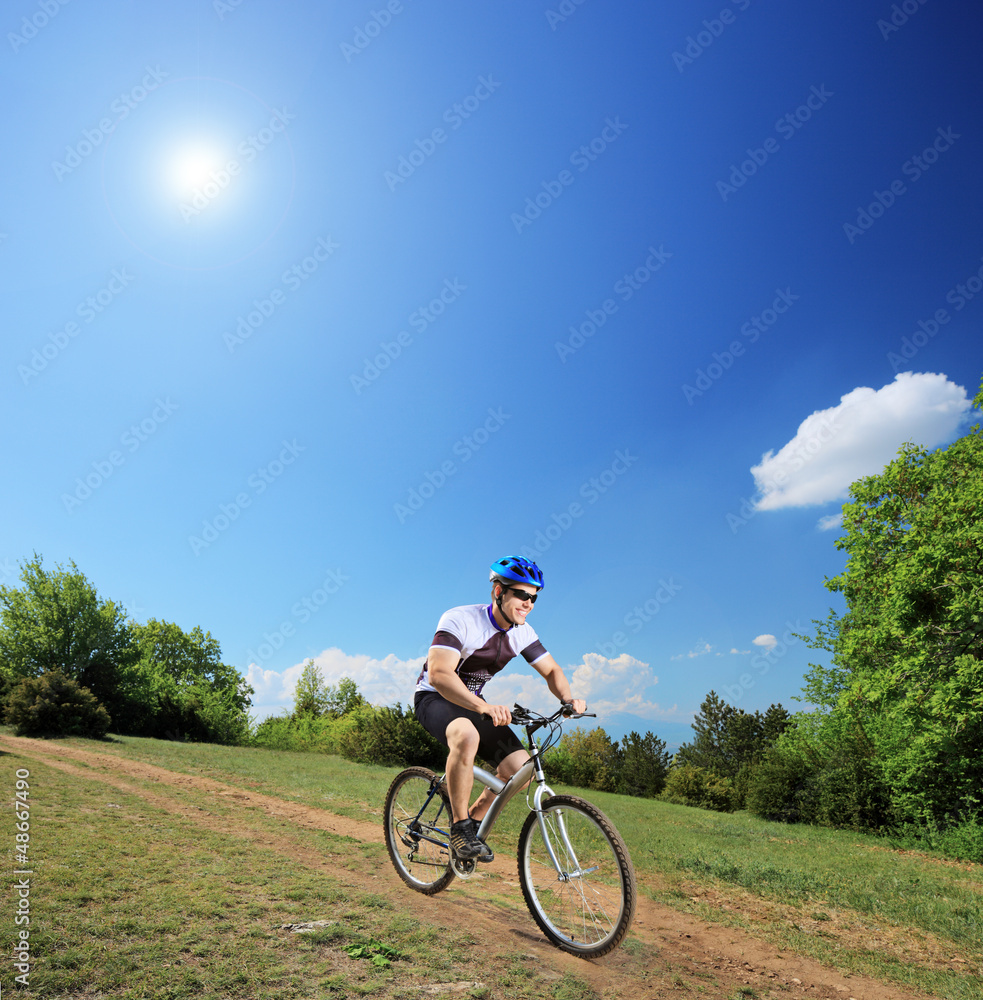Male bicyclist riding a mountain bike down hill on a sunny day Male bicyclist riding a mountain bike down hill on a sunny day