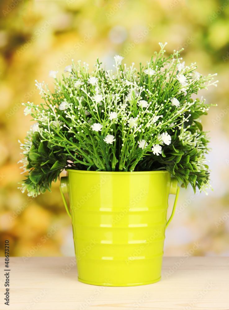 Decorative flowers in pot on bright background Decorative flowers in pot on bright background