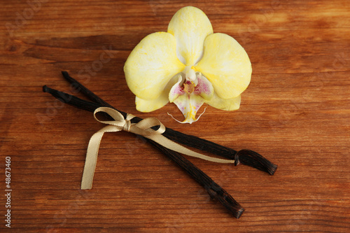 Vanilla pods with flower, on brown wooden background