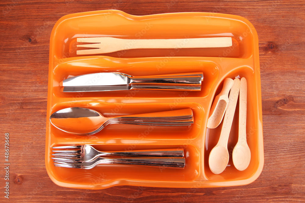 Orange plastic cutlery tray with checked cutlery and wooden Orange plastic cutlery tray with checked cutlery and wooden
