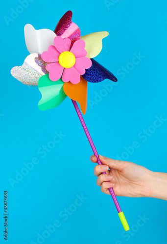 Colored pinwheel in hand on blue background © Africa Studio