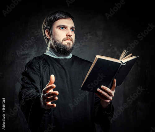 Priest with Prayer book against dark background