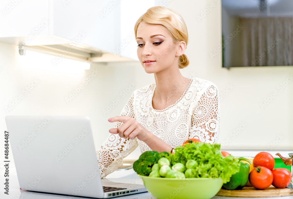 Woman looking for a recipe on the computer in the kitchen Woman looking for a recipe on the computer in the kitchen