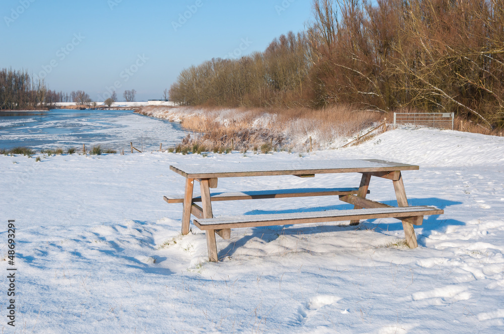 Freshly fallen snow on a wooden picnic table and bench