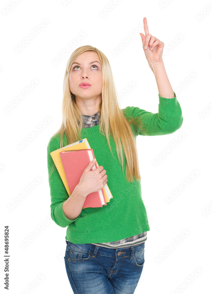 Happy student girl with books pointing up on copy space Happy student girl with books pointing up on copy space