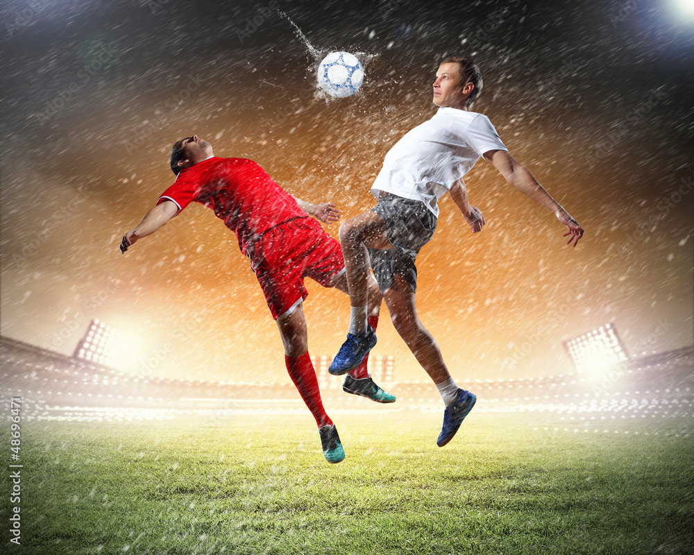 two football players striking the ball two football players striking the ball