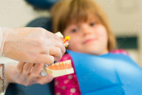 Dentist with toothbrush, denture, and little patient