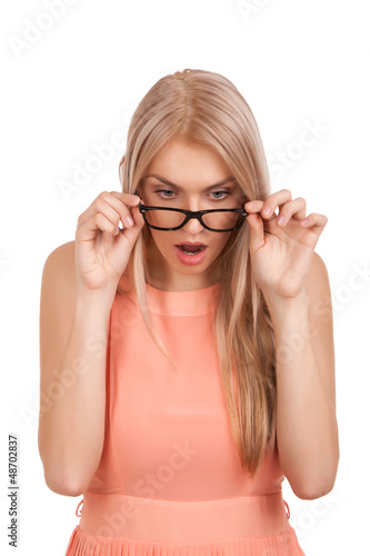 Surprised blond woman looking down over glasses