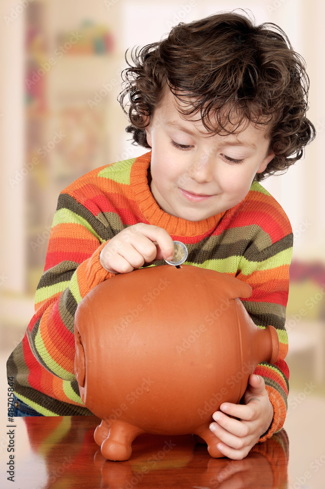 Fototapeta premium Little boy with his a big piggybank