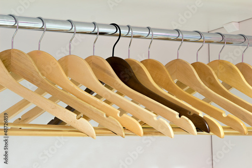 Yellow wooden hangers and one dark on a rod
