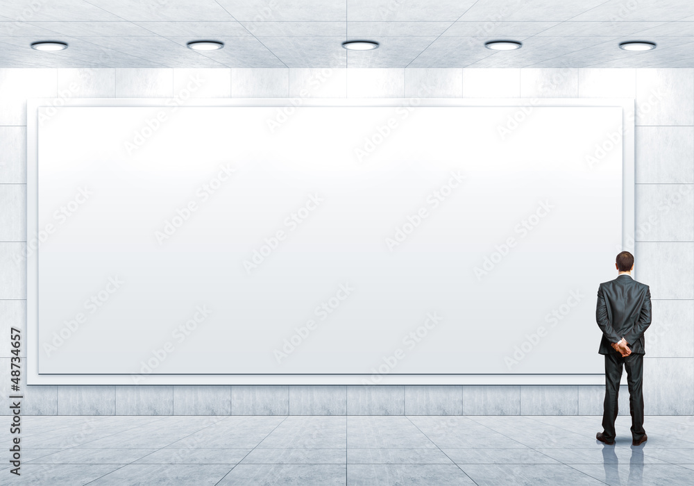 Business person standing near a blank billboard Business person standing near a blank billboard
