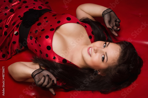 Pin-up girl lying on a red leather couch