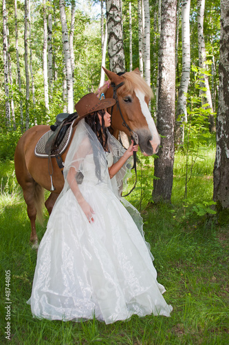 young woman in the dress of fiancee next to a horse © Galina