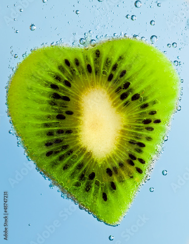 Fresh kiwi slices in water with bubbles