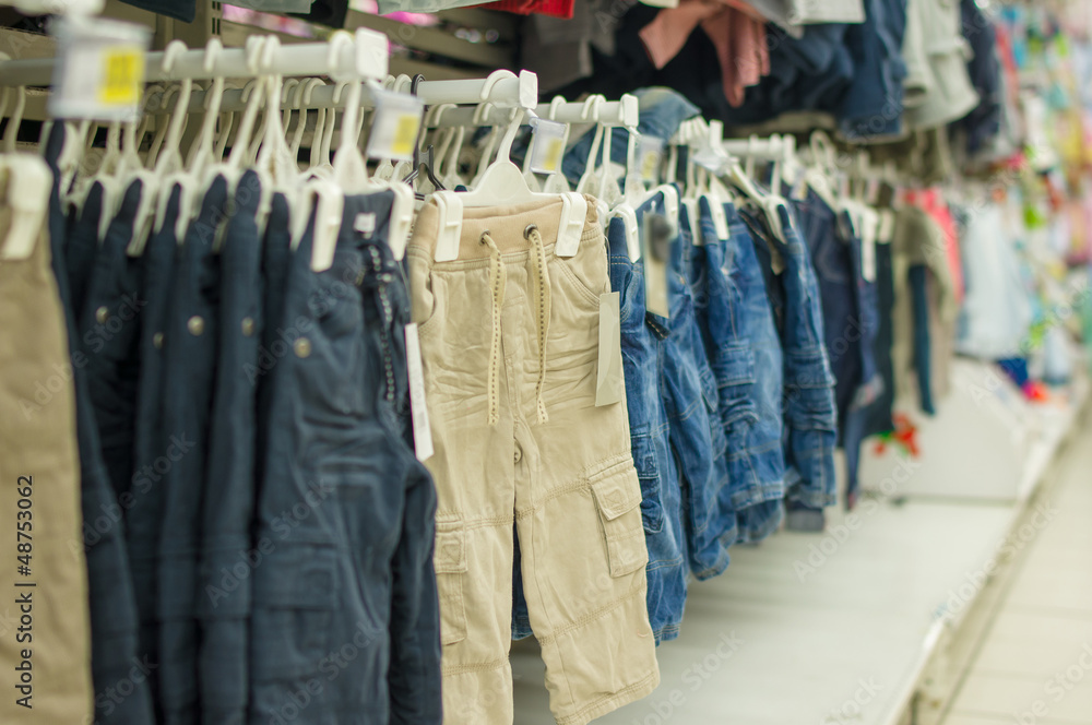 Trousers and jeans on stands in kids store