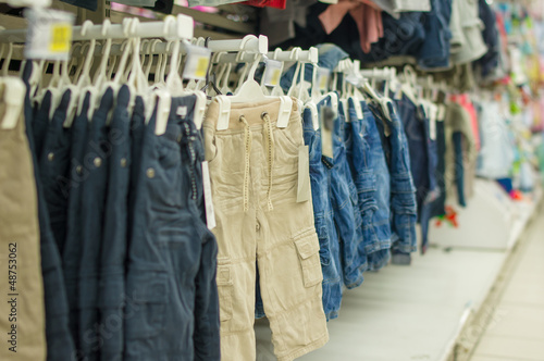 Trousers and jeans on stands in kids store © Joshhh