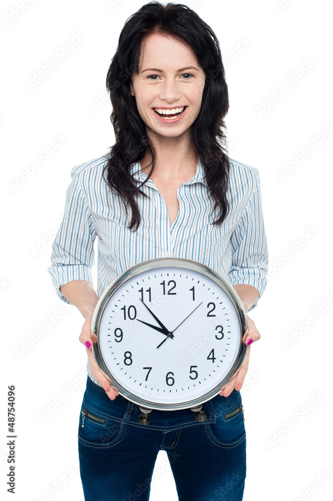 Cheerful brunette in casual presenting a wall clock Cheerful brunette in casual presenting a wall clock