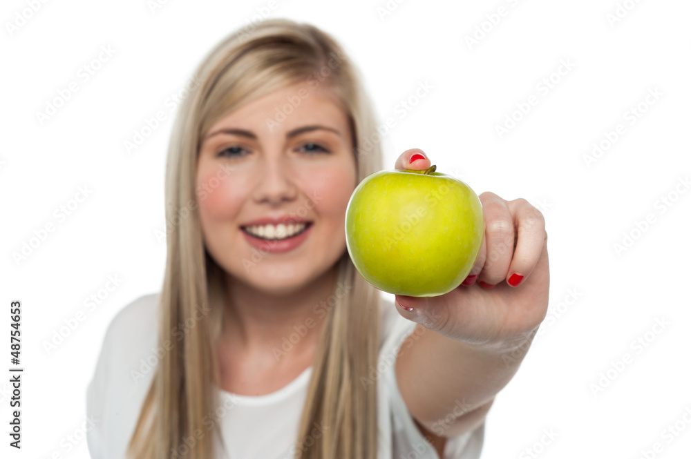 Smiling girl displaying fresh green apple to the camera Smiling girl displaying fresh green apple to the camera