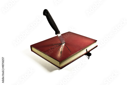 Book stabbed by knife and bleeding ink