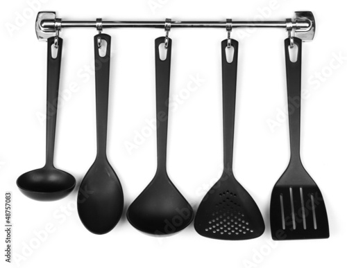 Black kitchen utensils on silver hooks, isolated on white
