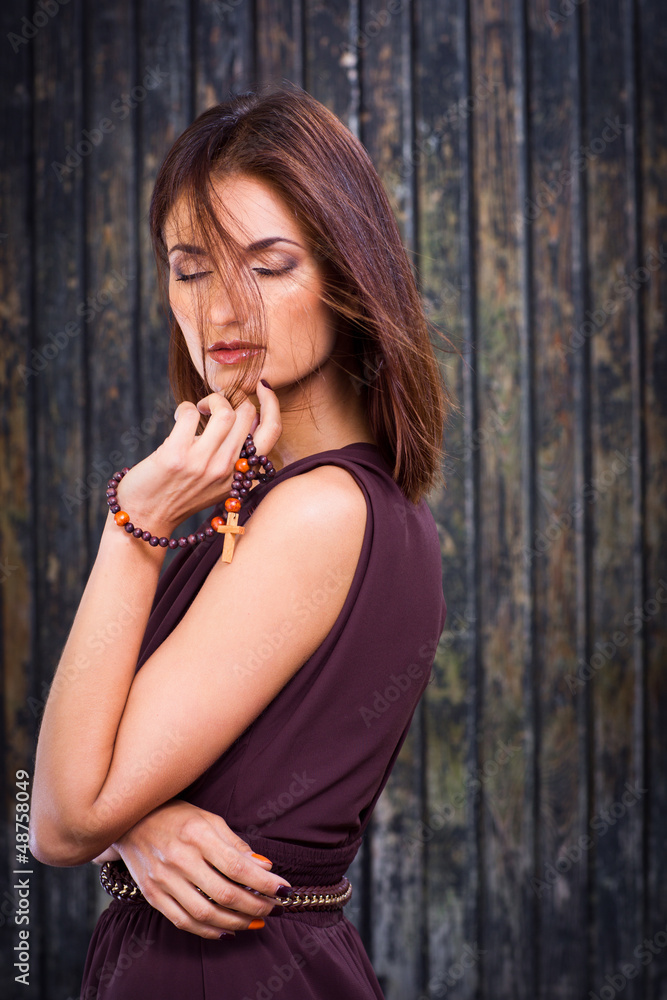 beautiful girl with christian beads against old wooden wall beautiful girl with christian beads against old wooden wall
