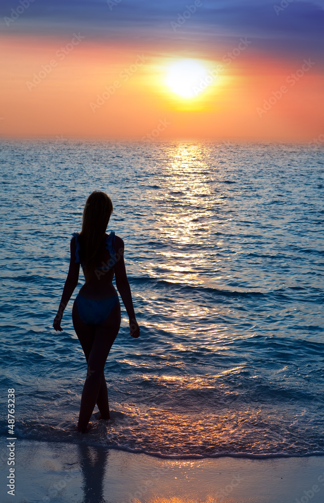 Silhouette of the sexual woman going at ocean towards to sunset Silhouette of the sexual woman going at ocean towards to sunset