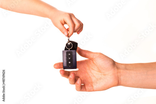 Male hand holding a car key and handing it over isolated