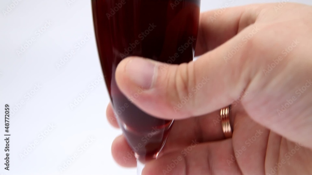 Hand shaking red wine glass half full with wine Hand shaking red wine glass half full with wine