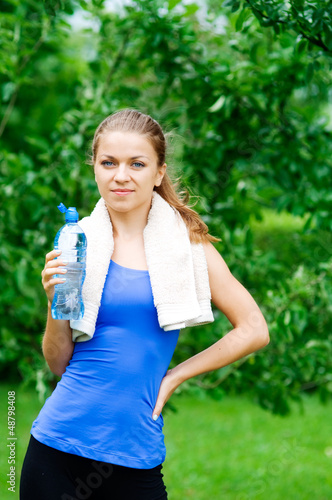 Smiling woman with water bottle after workout