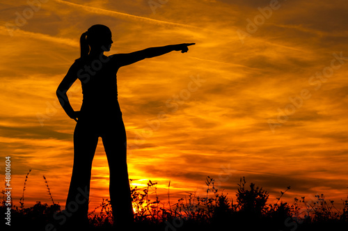 Silhouette of the young woman pointing to something