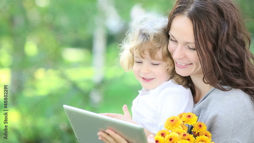 Happy family using tablet PC outdoors in spring park Happy family using tablet PC outdoors in spring park
