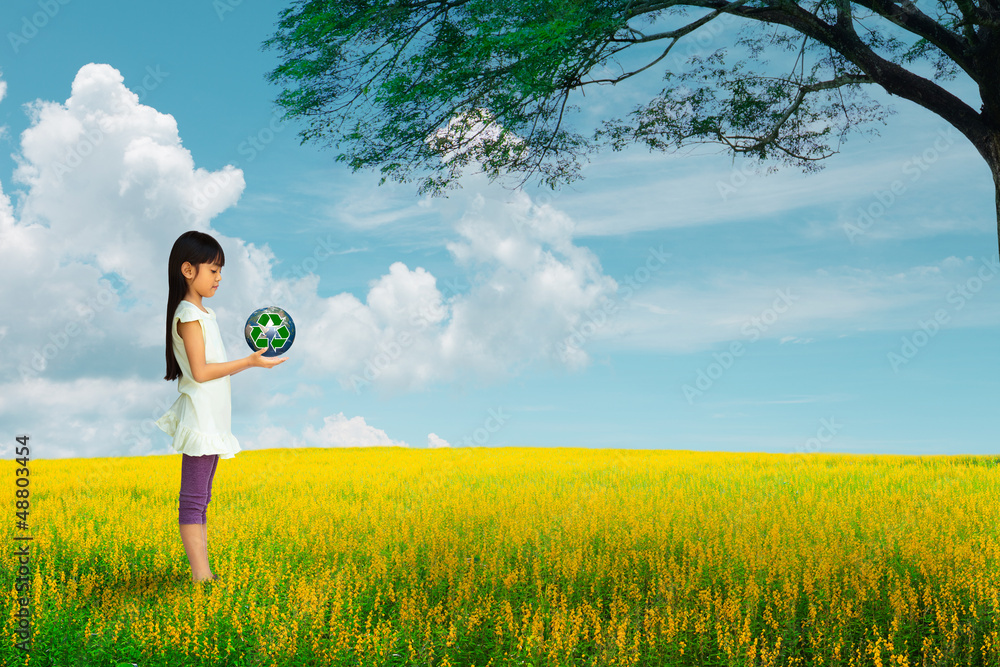 Little girl holding earth with recycle symbol at flower field