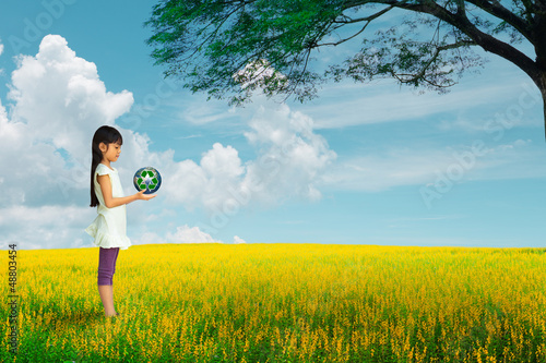 Obraz na płótnie Little girl holding earth with recycle symbol at flower field w salonie