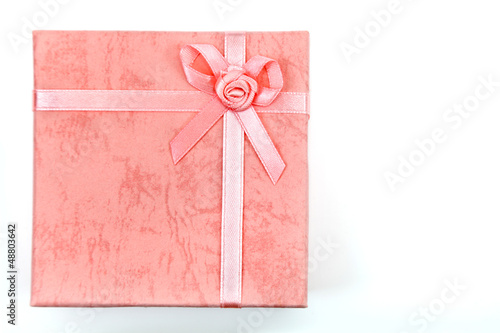 Różowe pudełko z kokardką na białym tle.