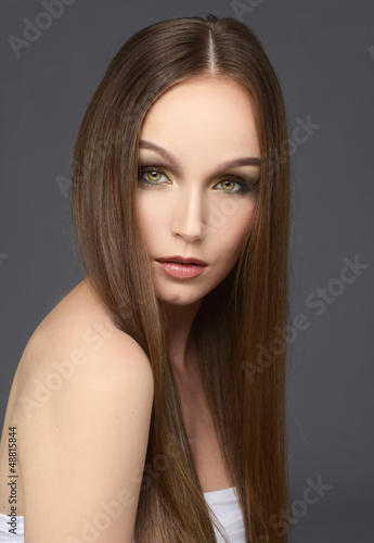 Attractive girl with long hair on gray