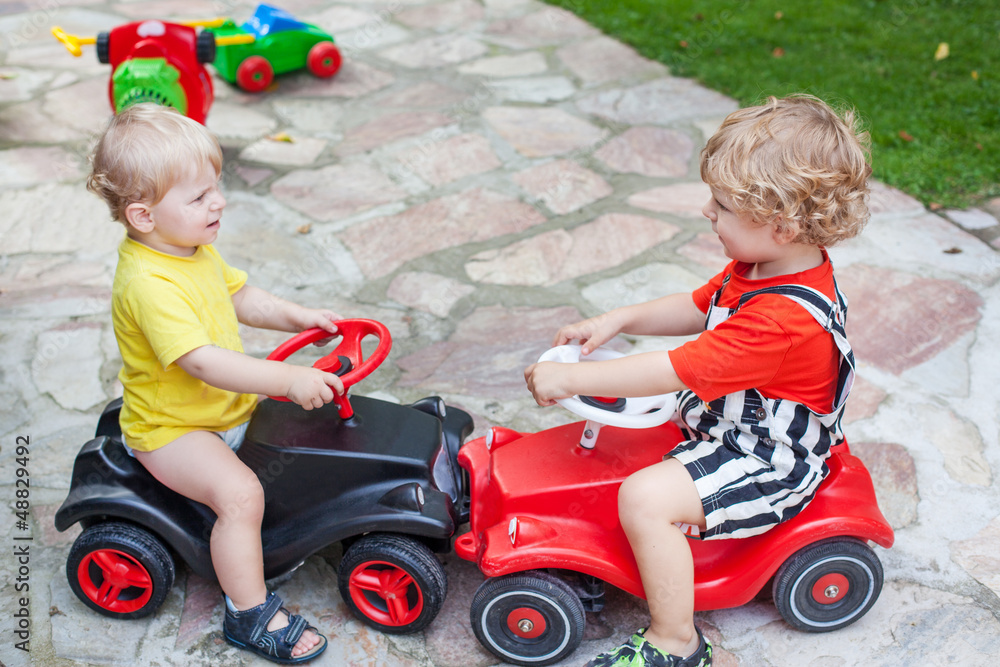 Fototapeta premium Two little brothers toddlers playing with cars