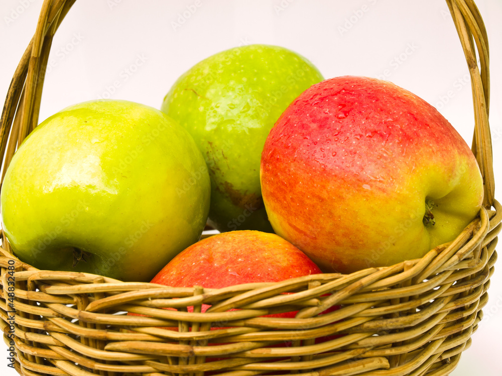 Green and red apples in a basket isolated on white background