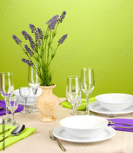 Table setting in violet and green tones on color background