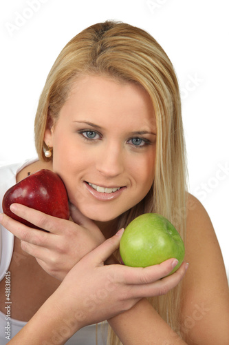 Blond woman choosing between red and green apples