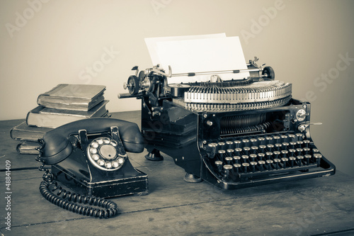 Bild auf Leinwand Vintage phone, old typewriter, books on table desaturated photo