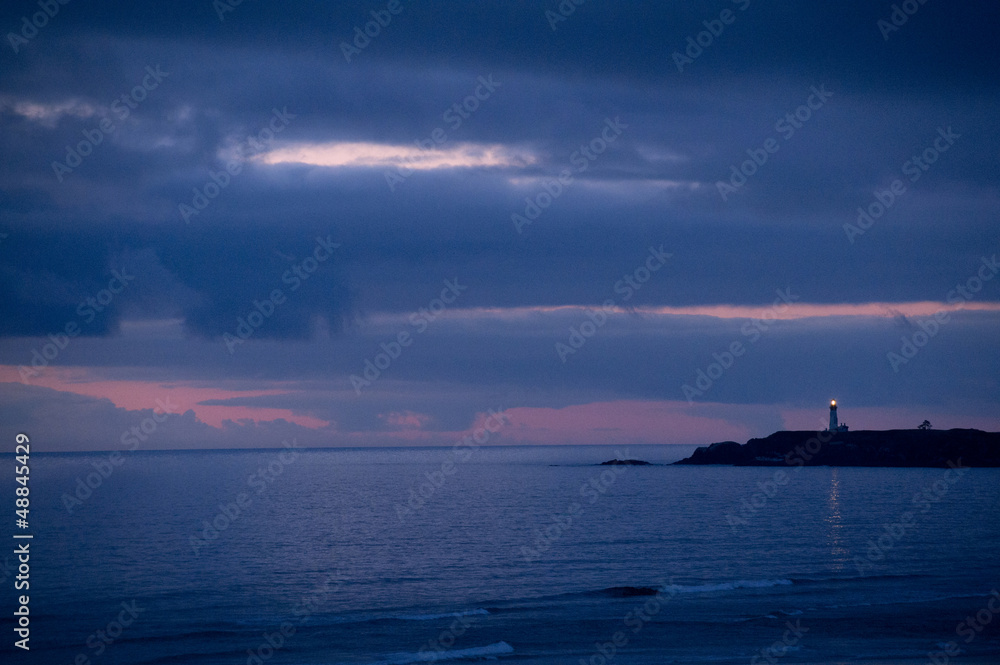 Lighthouse beaming from coastline at night Lighthouse beaming from coastline at night