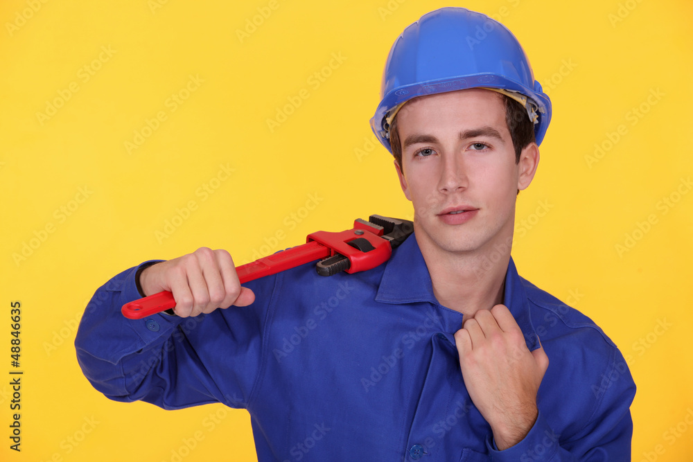 Young worker with wrench in the shoulder Young worker with wrench in the shoulder